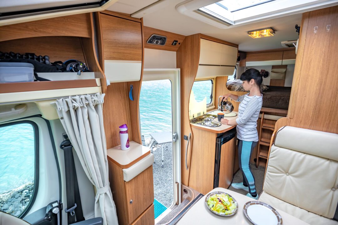 woman cooking in camper, motorhome interior